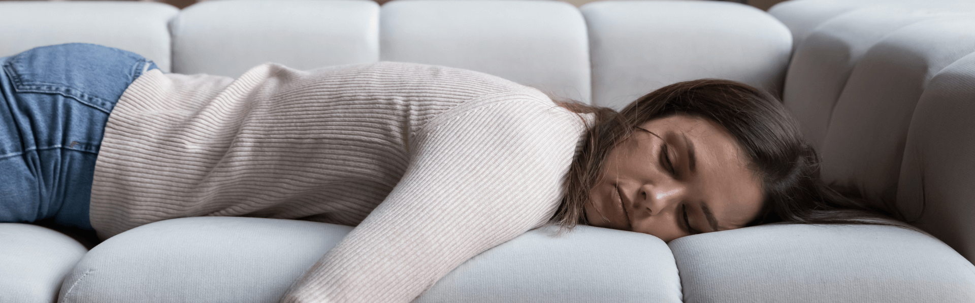Frau mit Long Covid liegt erschöpft auf dem Sofa.