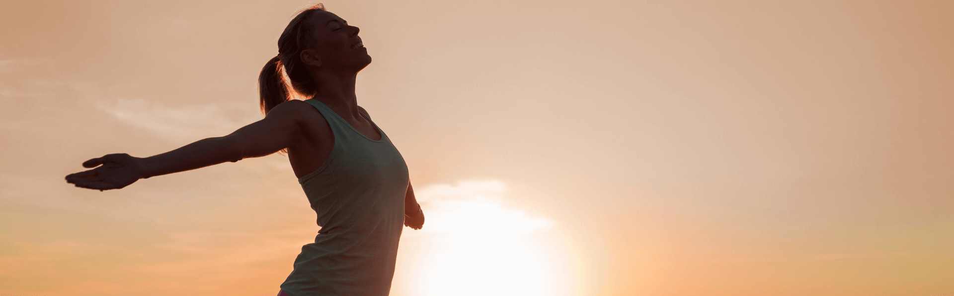 Frau streckt beide Arme weit von sich und atmet tief ein als Teil ihrer Longevity-Maßahmen.