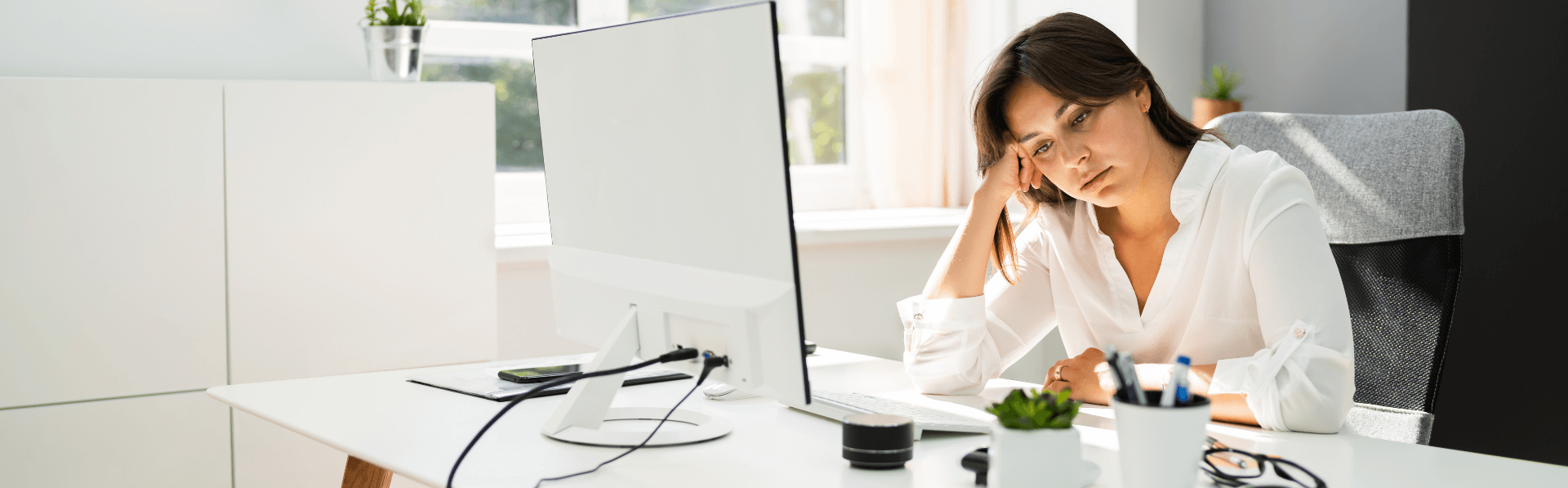 Frau leidet unter Stress und sitzt am Schreibtisch im Büro.