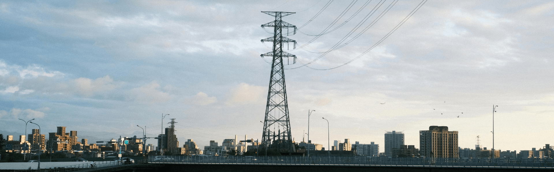 Strommast vor einer Großstadt.