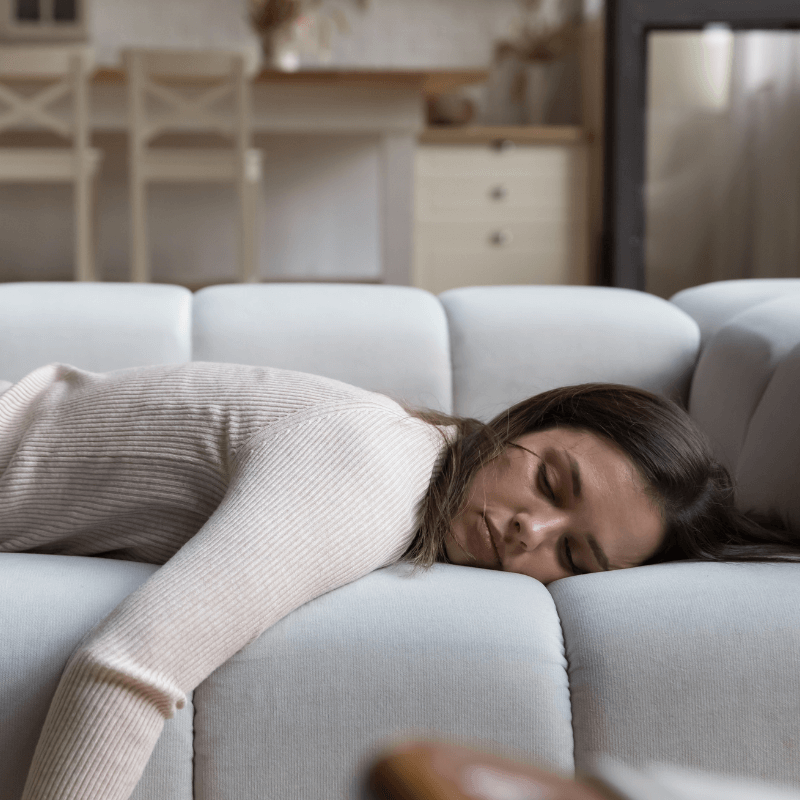 Frau mit Long Covid liegt erschöpft auf dem Sofa.