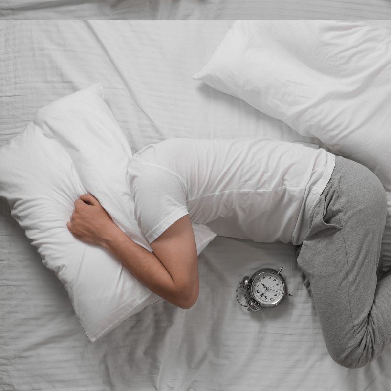 Mann mit Schlafstörungen wälzt sich im Bett.