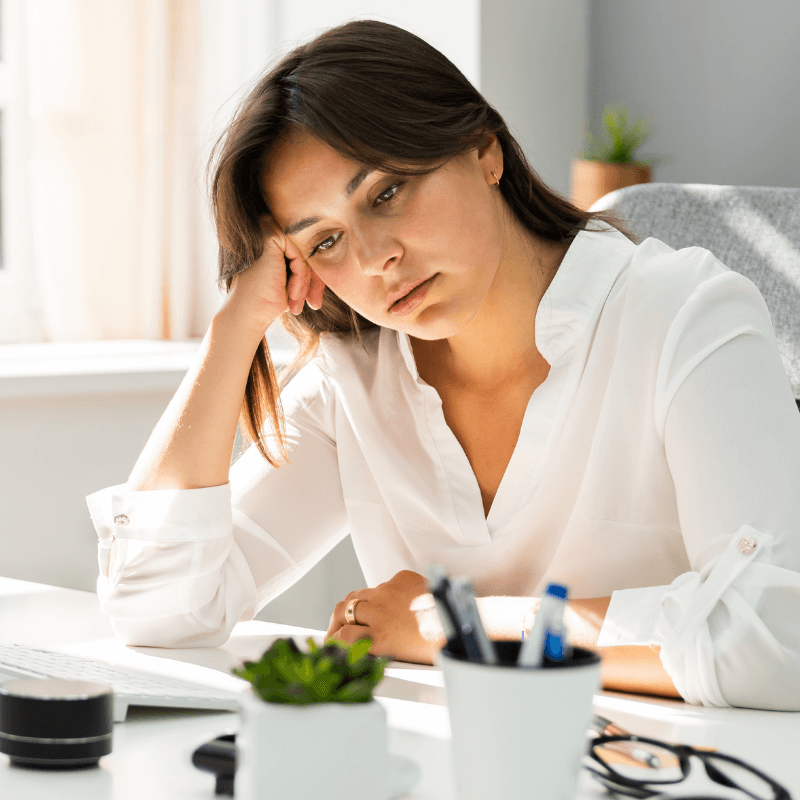 Frau leidet unter Stress und sitzt am Schreibtisch im Büro.