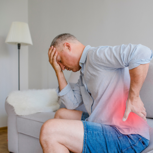 Mann halt sich an schmerzendem Kopf und Rücken fest.